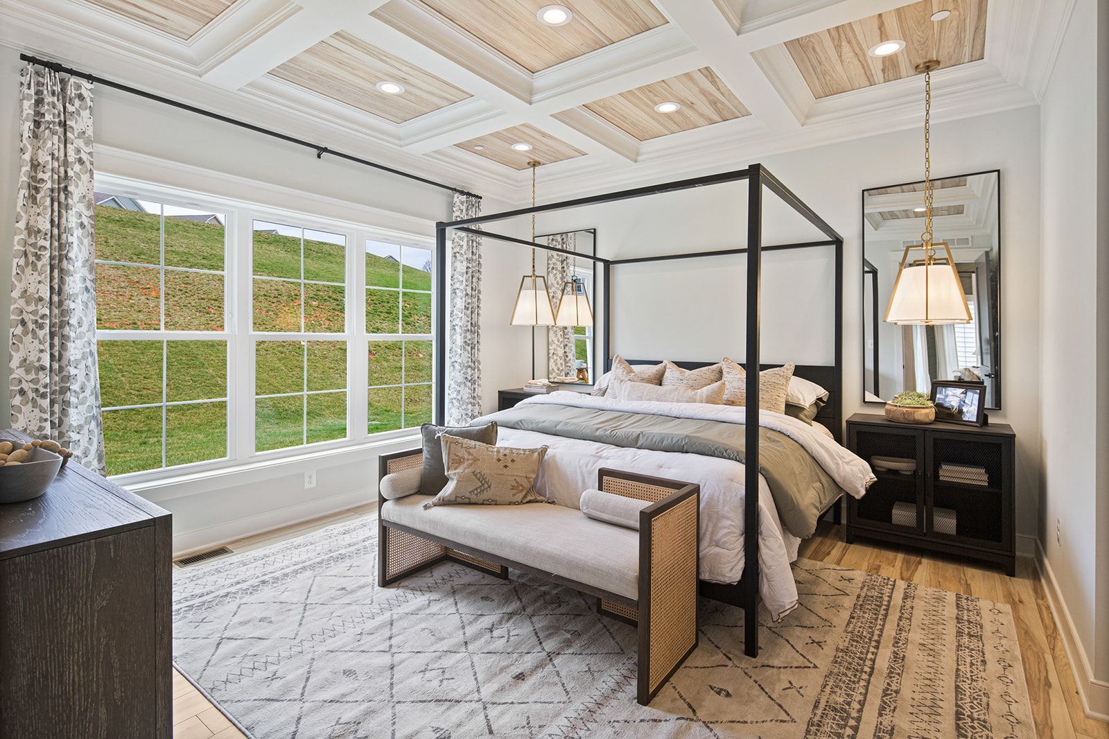 Bedroom with canopy bed, patterned rug, large windows, and decorative ceiling.