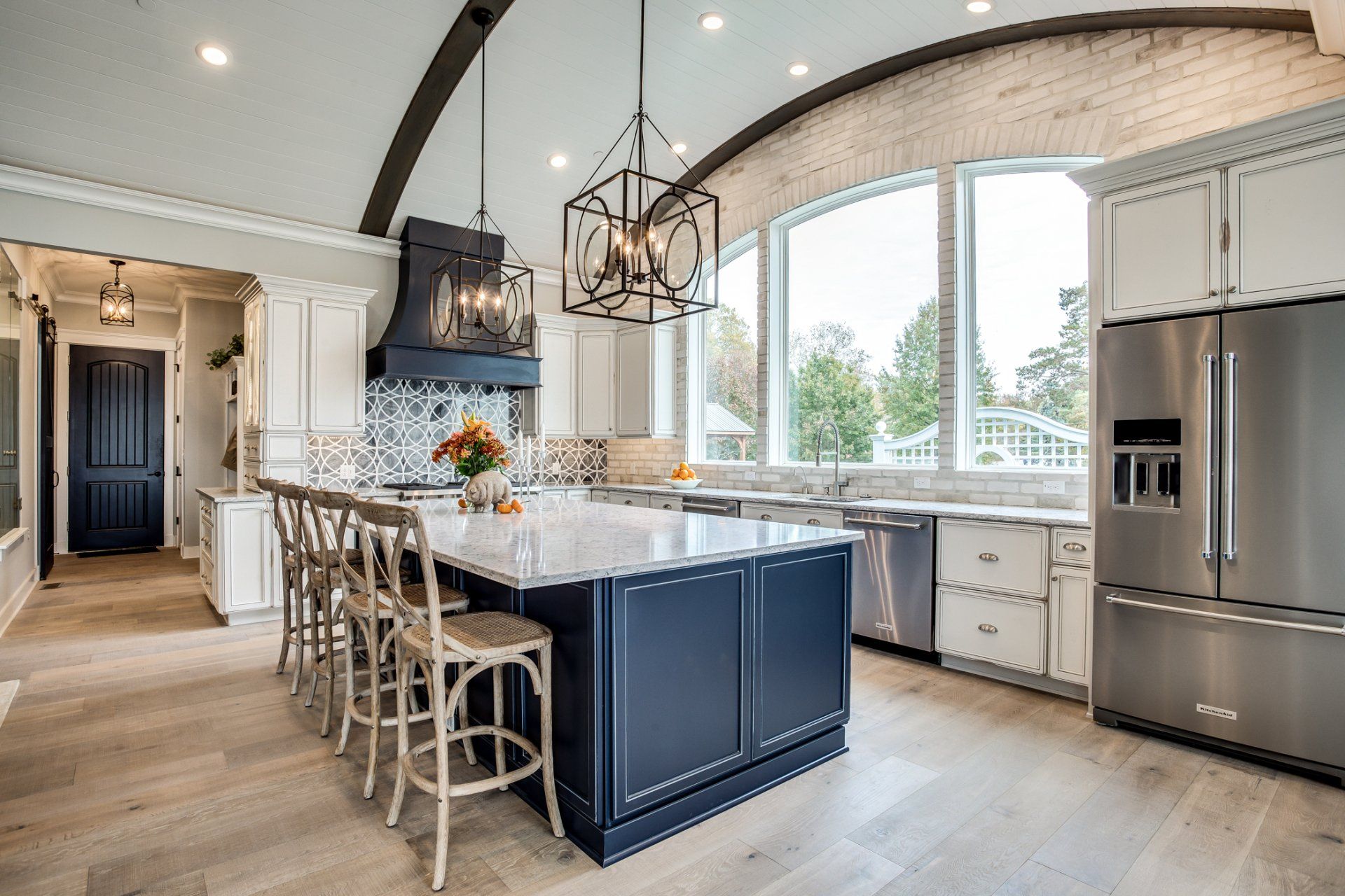 Elegant kitchen with blue island, white cabinets, and large window.