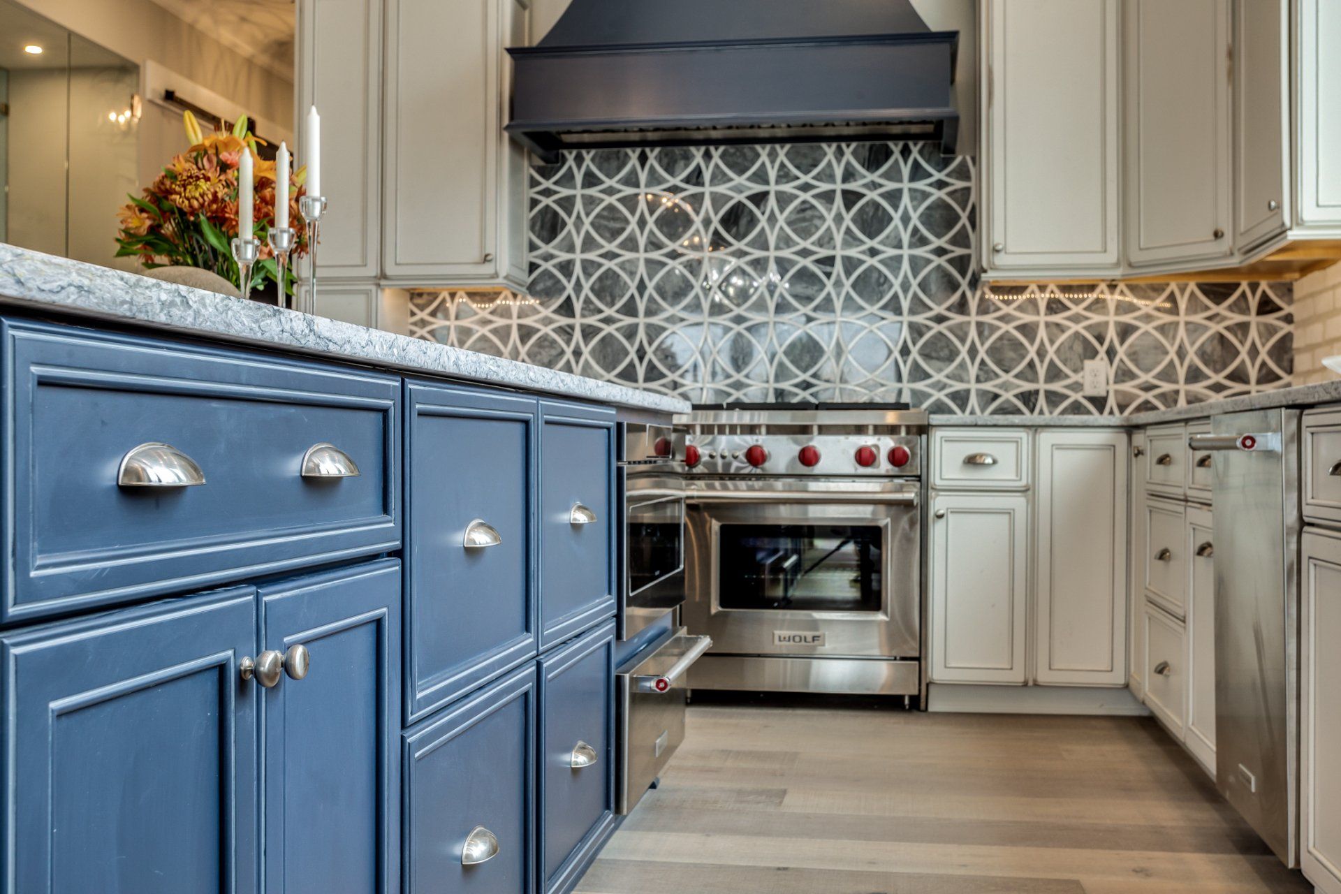 Blue and white kitchen with patterned tile backsplash and stainless steel appliances.