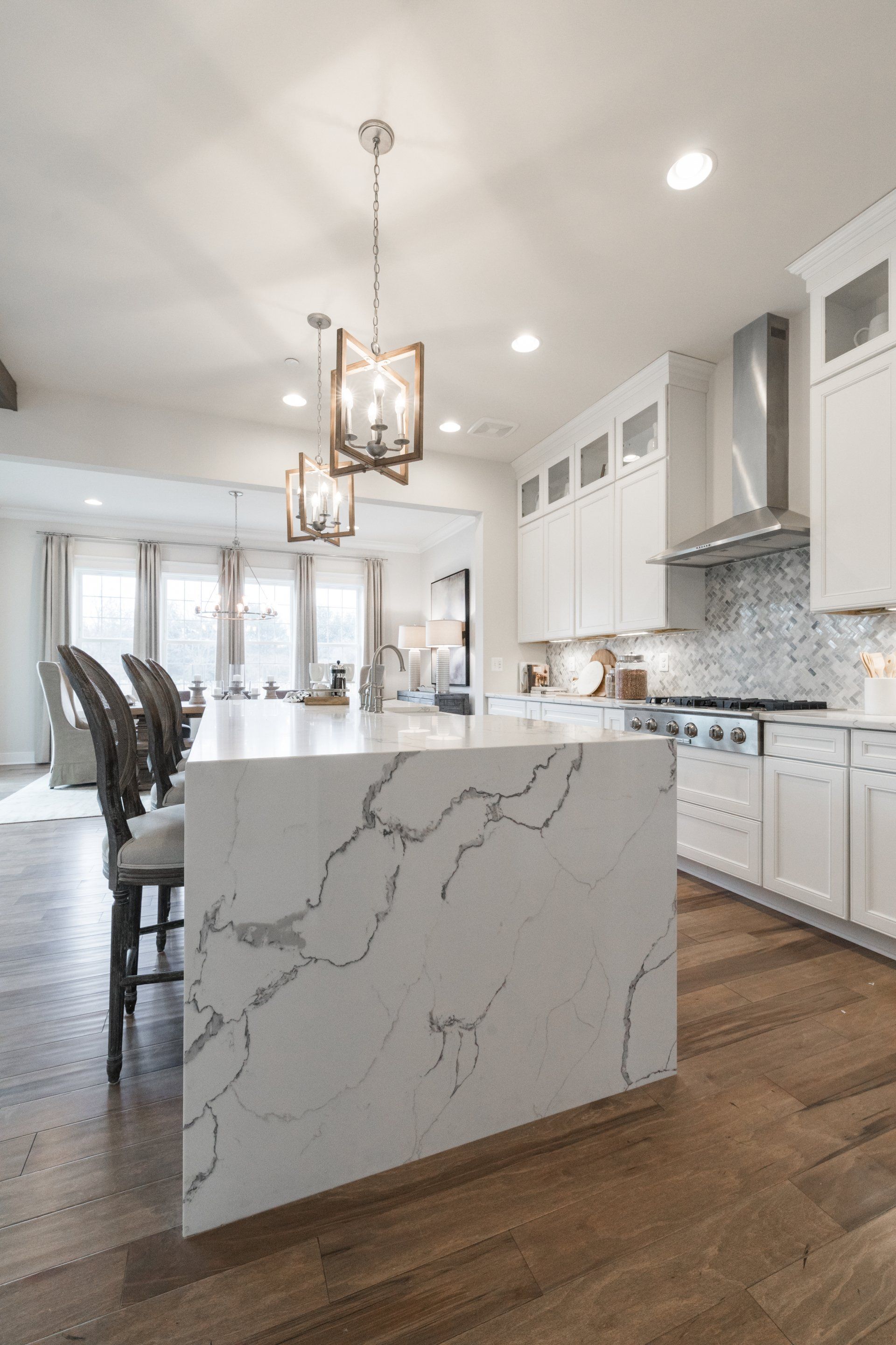 Modern white kitchen with large island and wood floors.