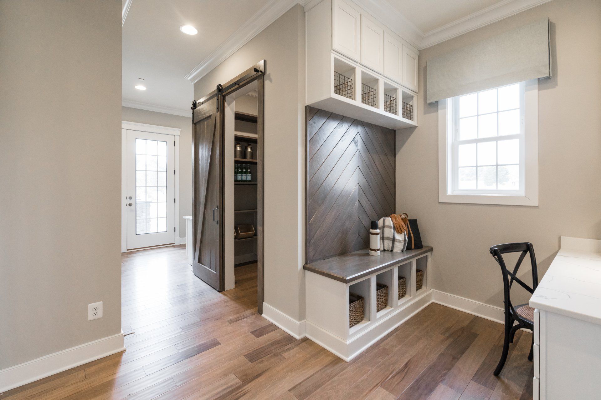 Mudroom with built-in bench, storage, sliding barn door to pantry, desk, and window.