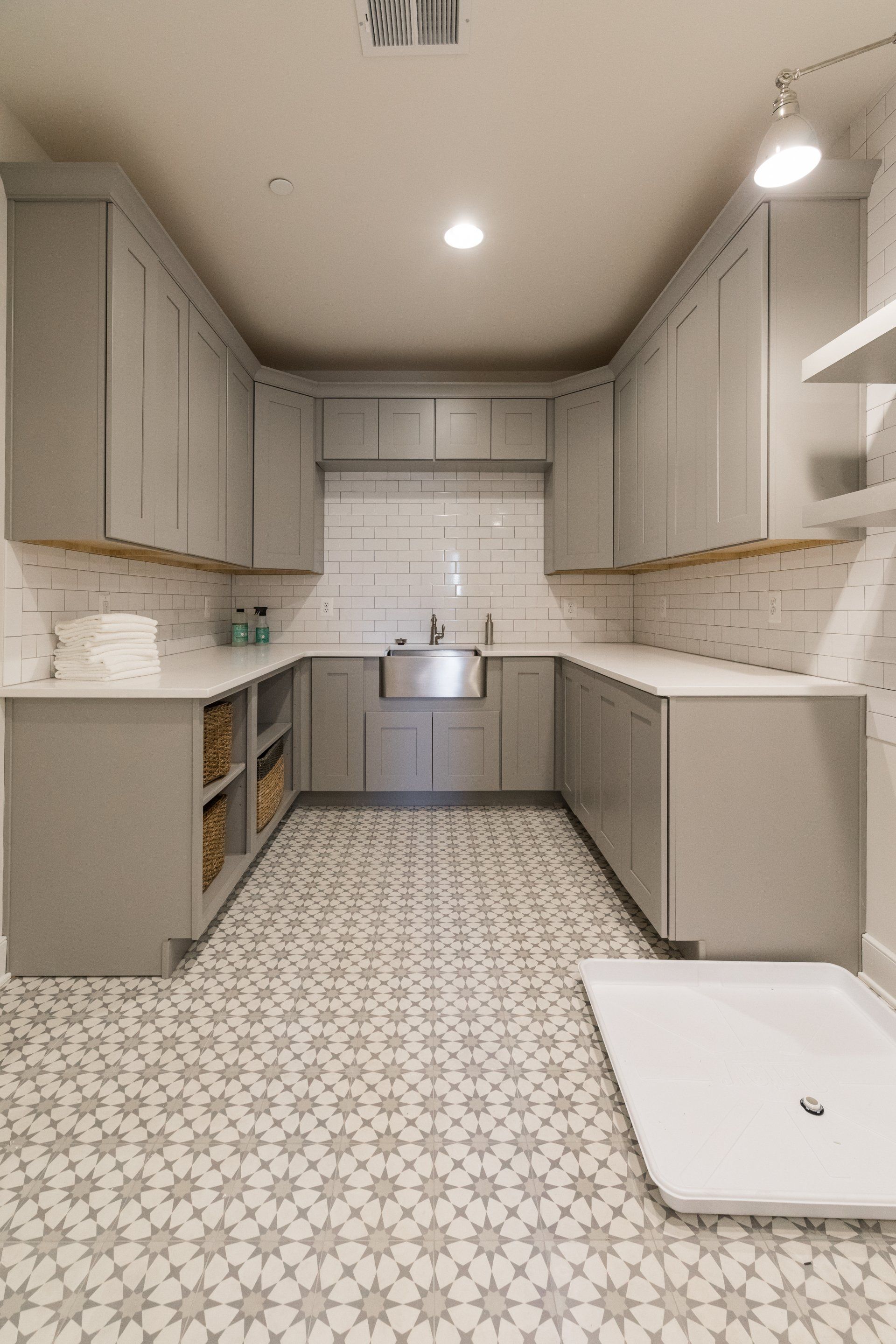 U-shaped laundry room with gray cabinets, patterned floor, and stainless steel sink.