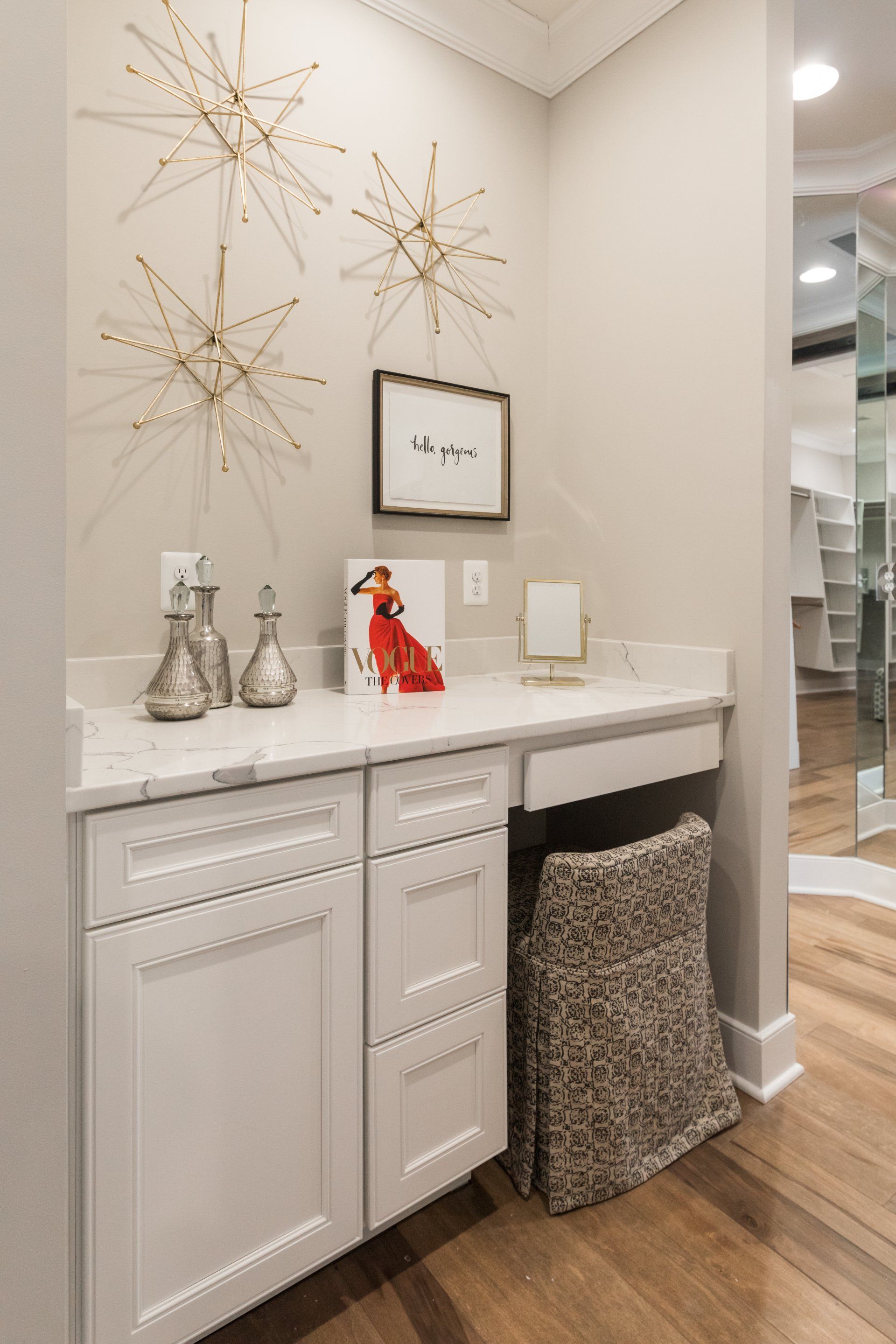 Vanity area in a closet with white cabinets, starburst wall decor, and a leopard print stool.