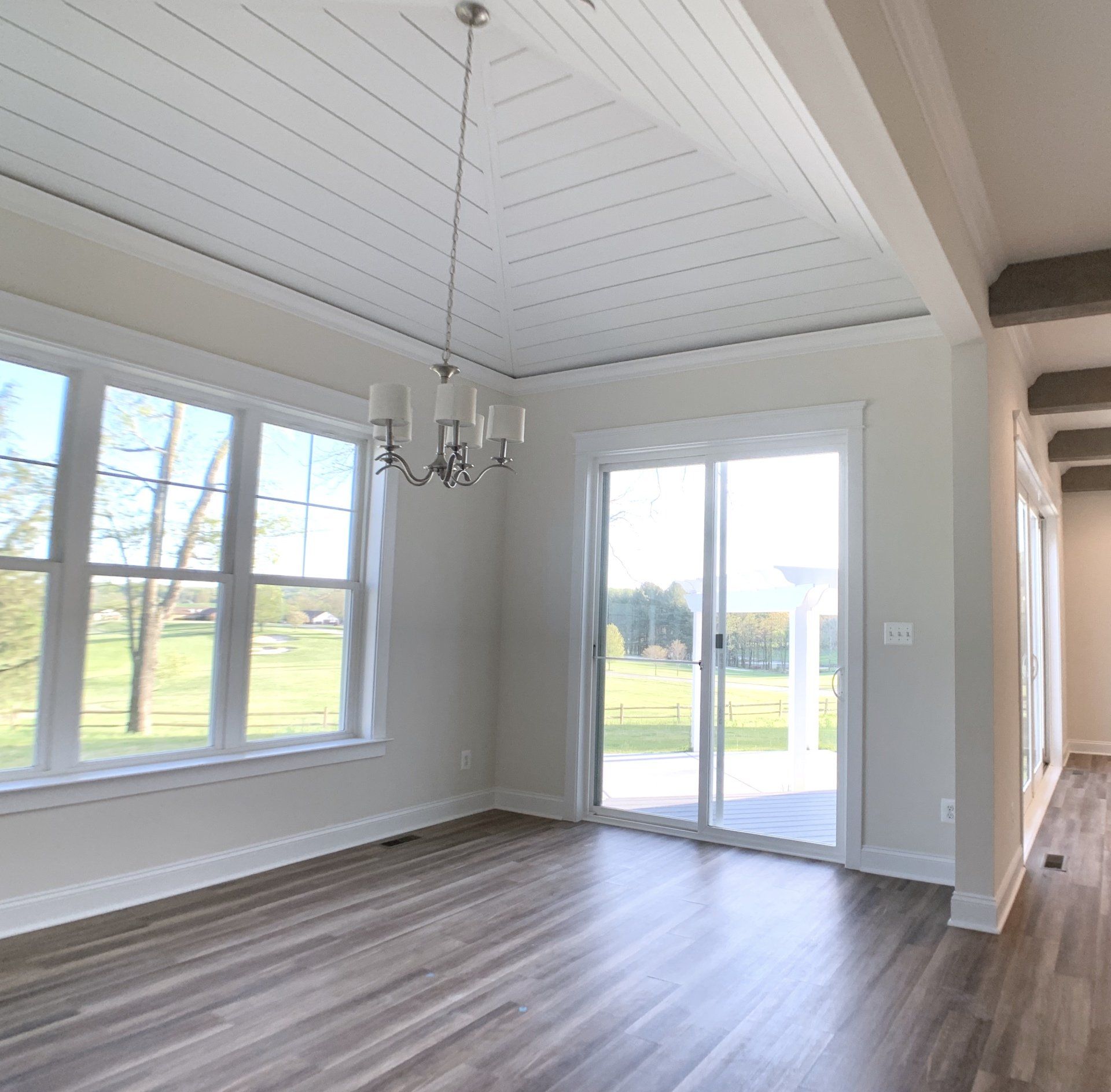 Dining room with gray wood floor, white walls, and a white ceiling with a chandelier.