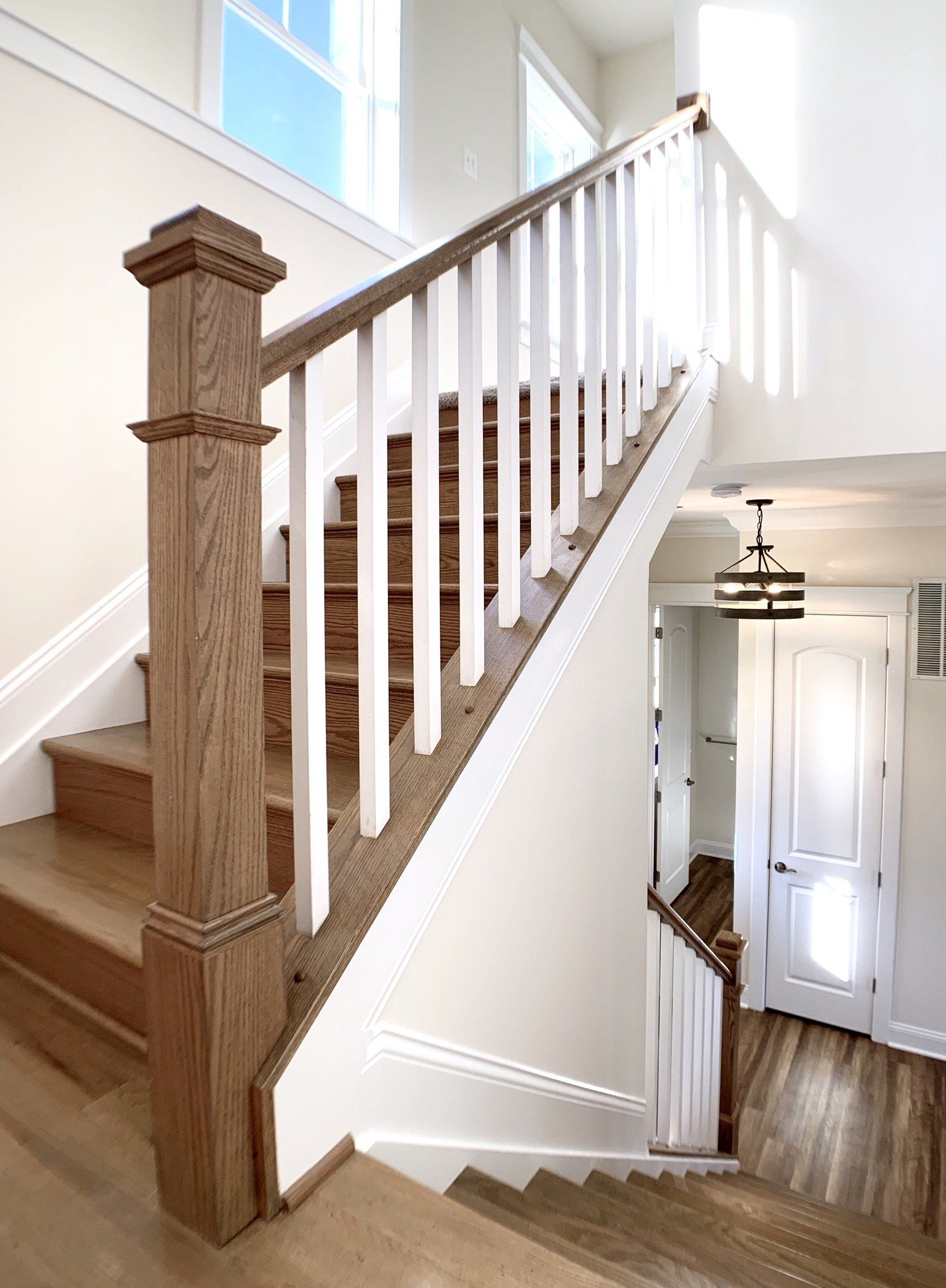 Wooden staircase with white railing and newel post in a bright, modern home.