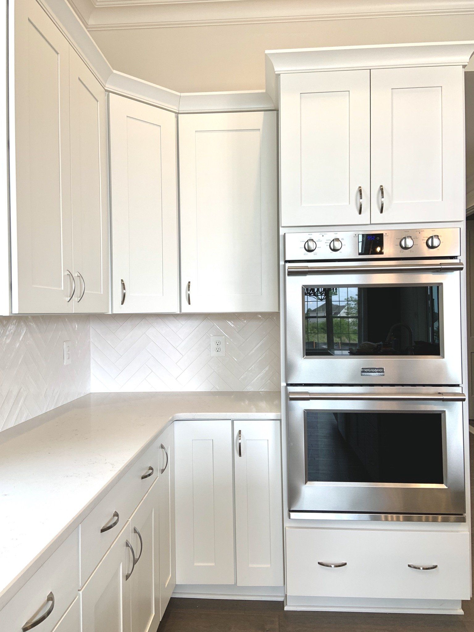 White kitchen with cabinets, countertops, oven, and backsplash.