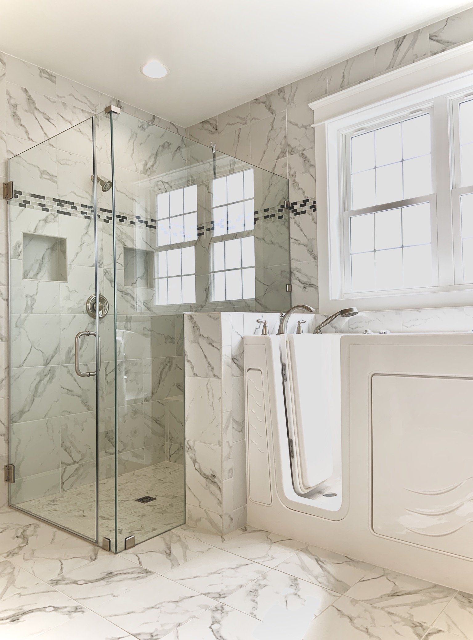 Marble-tiled bathroom with a glass shower, window, and built-in bathtub.