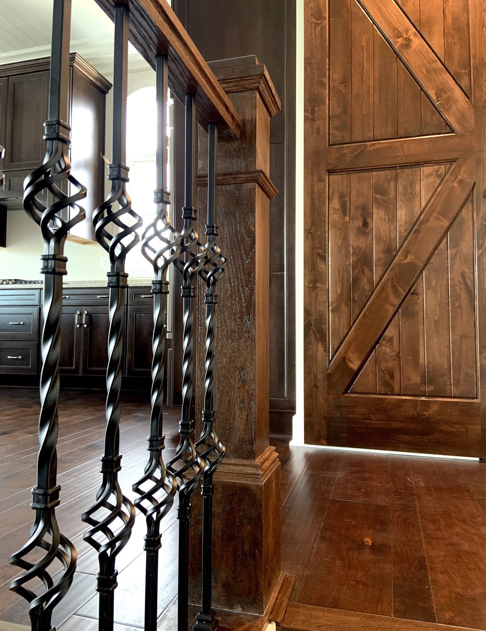 Dark wrought iron railing with basket details, next to a stained wooden door.