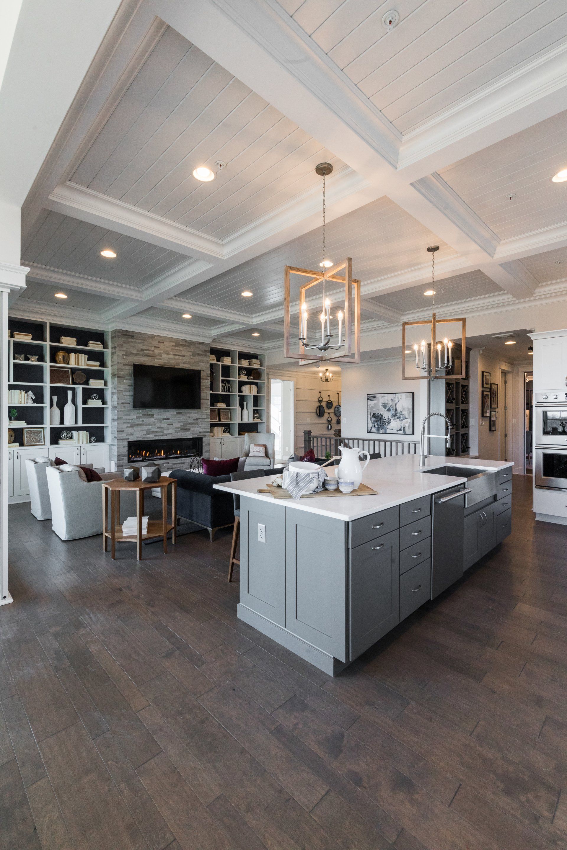 Spacious open-plan kitchen with gray island, hardwood floors, and living area with fireplace and built-in shelves.