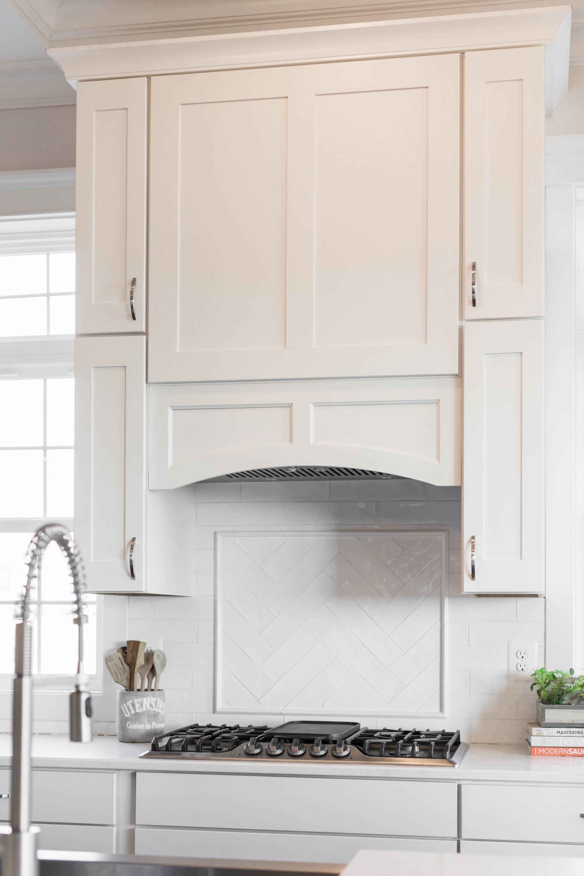 White kitchen with a gas stovetop, white cabinets, and a tiled backsplash.
