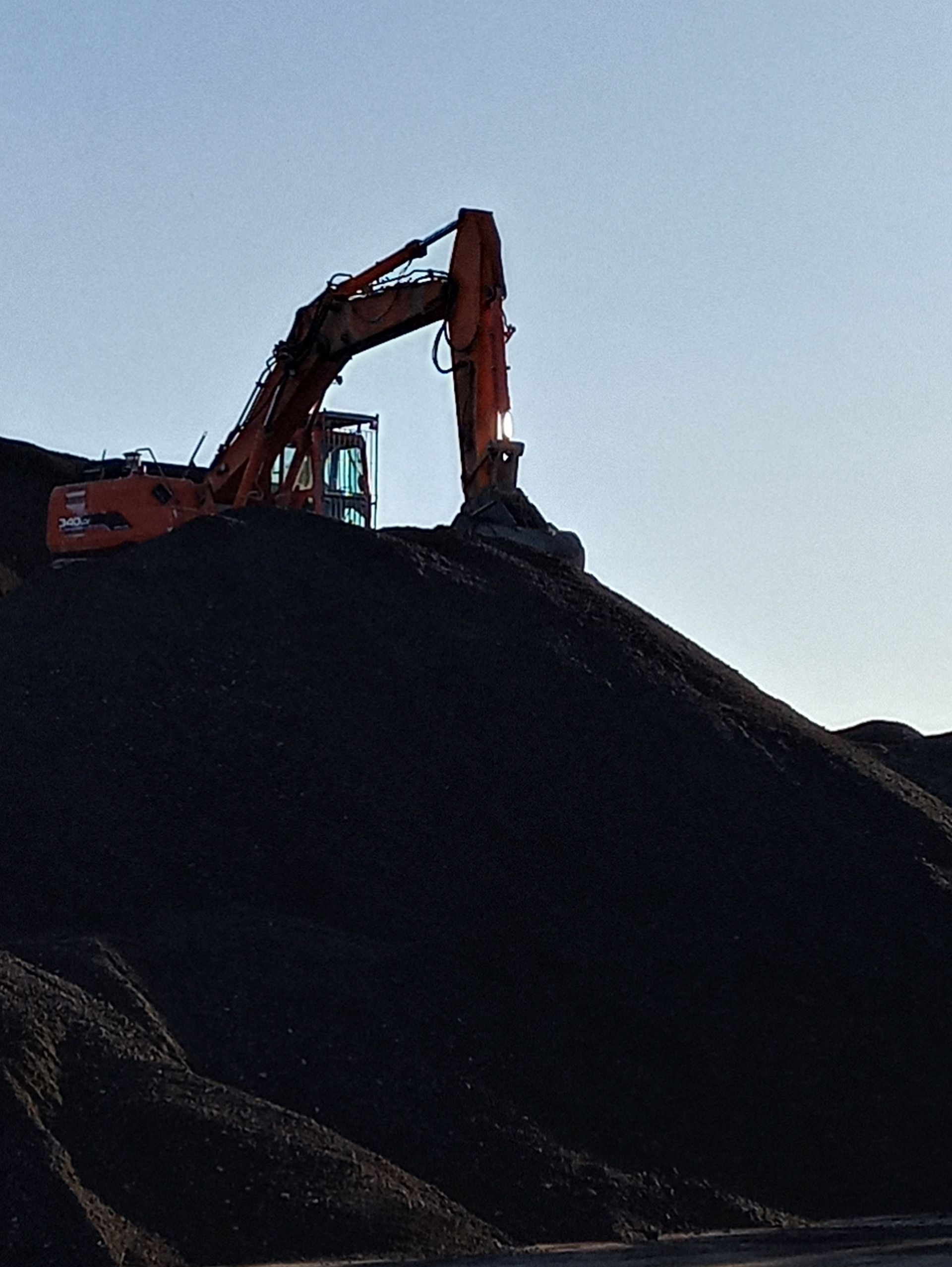 Un escavatore sta lavorando su un mucchio di terra