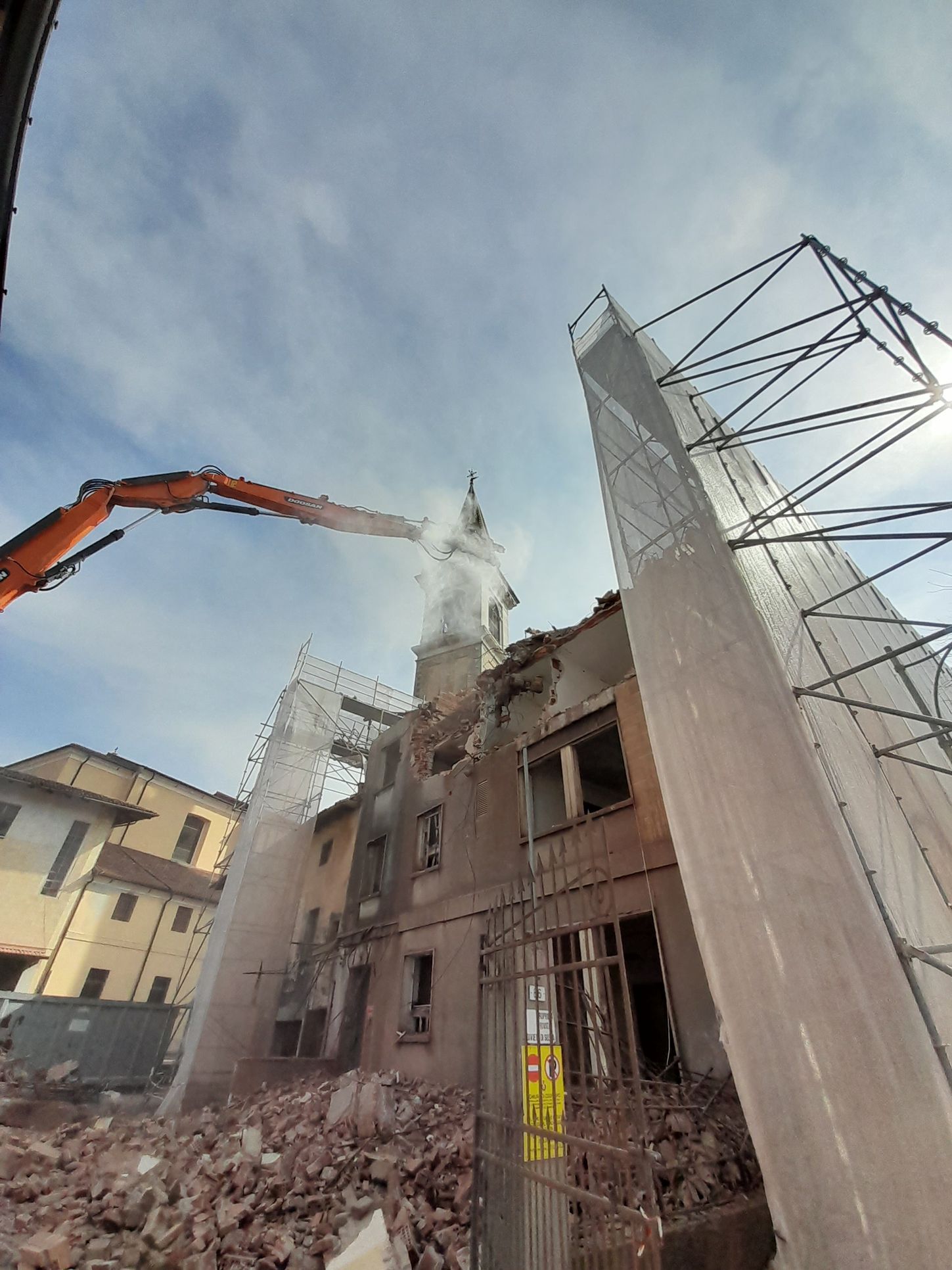 Un grande edificio viene demolito da una gru.