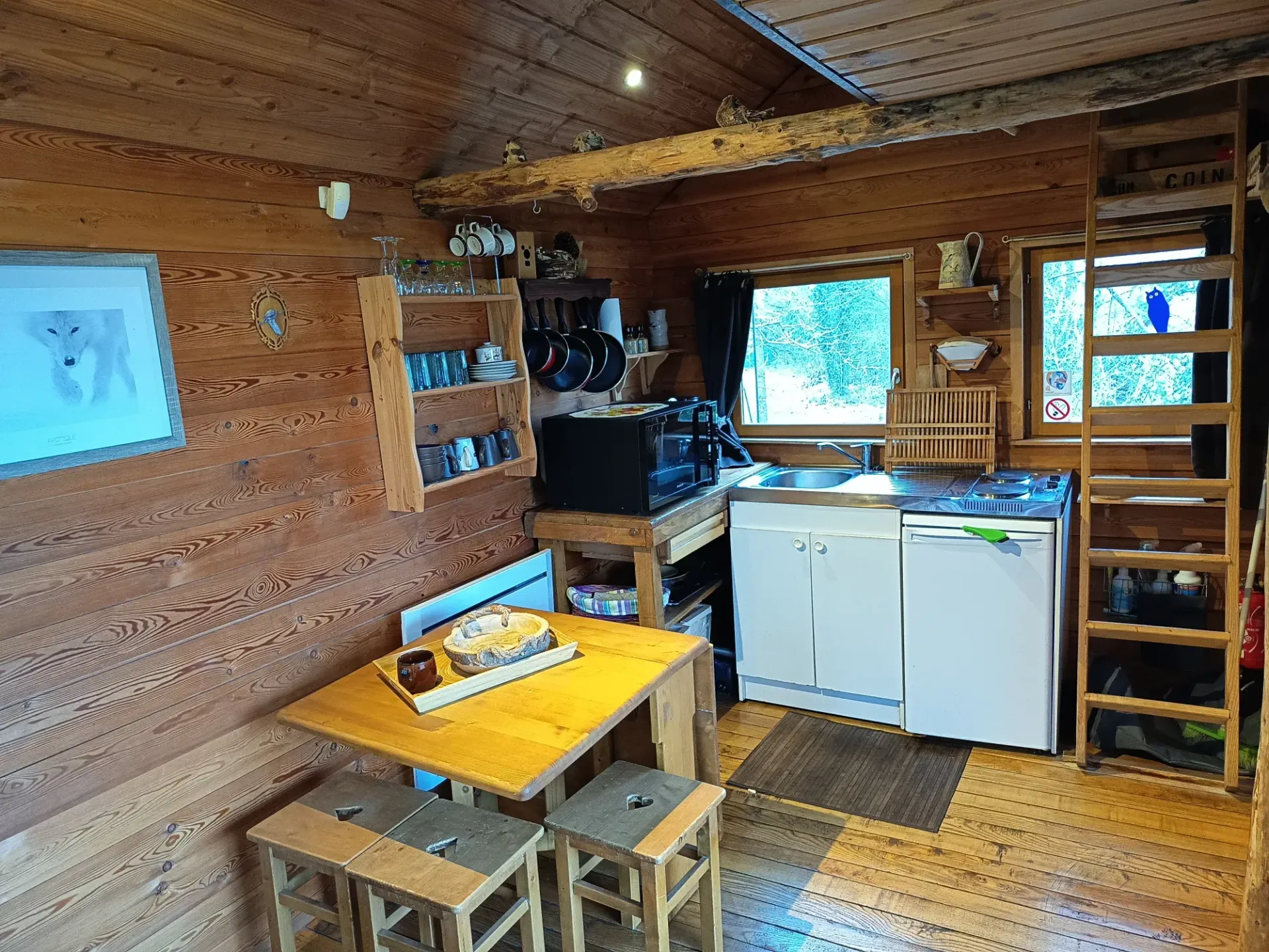 Klein houten hutje met keuken, tafel en ladder naar de bovenverdieping.