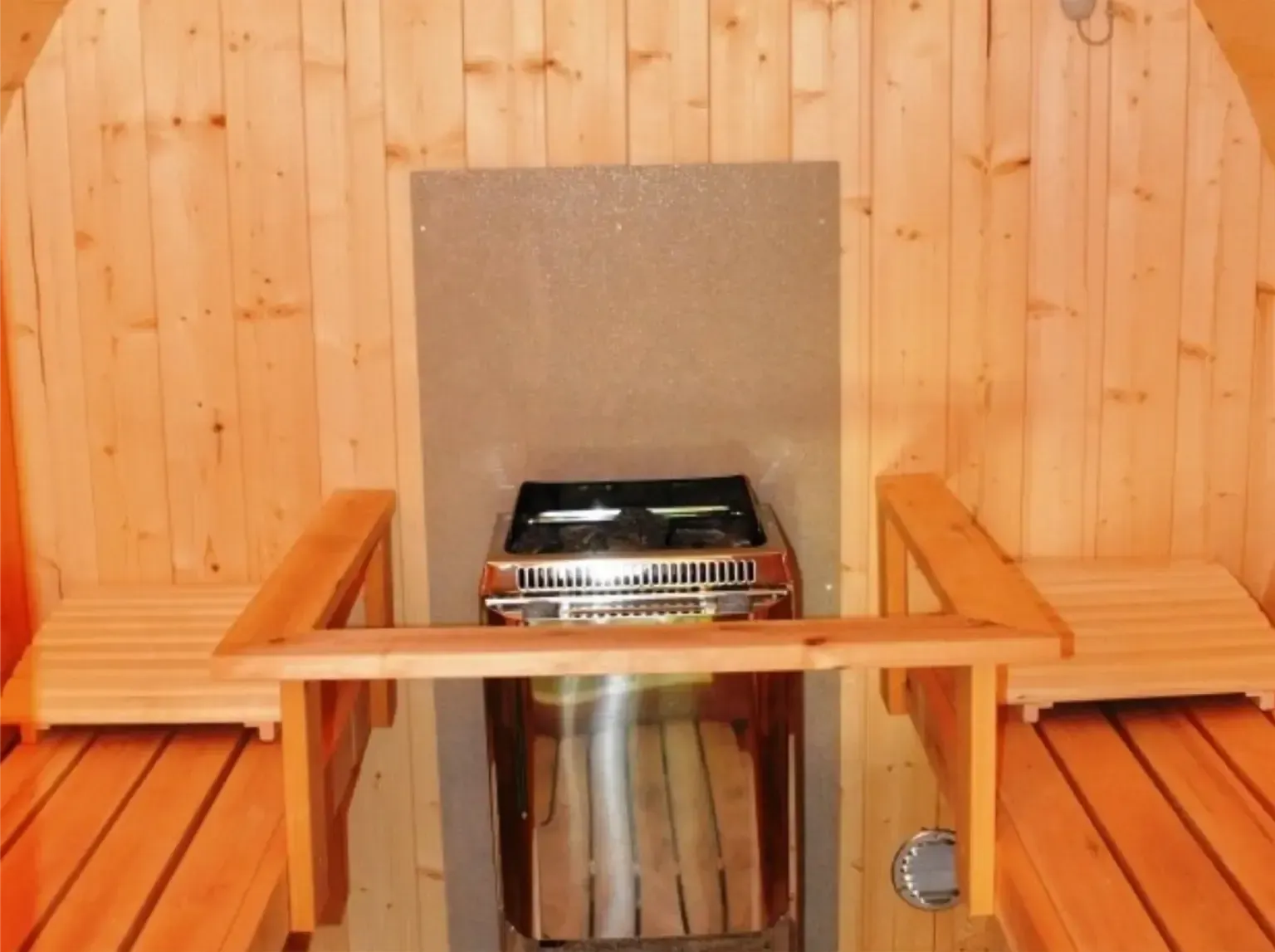 Interieur van een sauna met houten banken en een roestvrijstalen kachel.