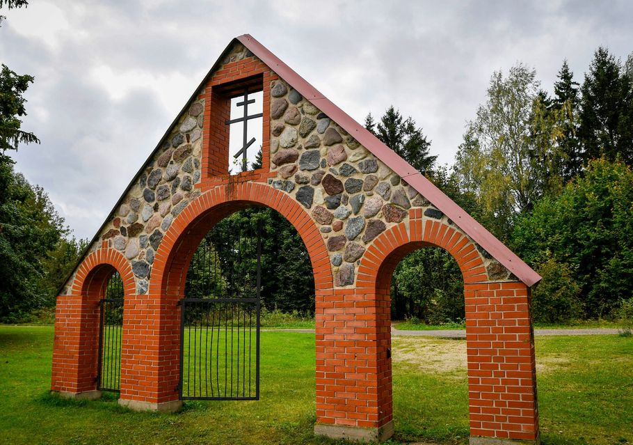 Small brick-and-stone archway structure with three arches in a grassy park