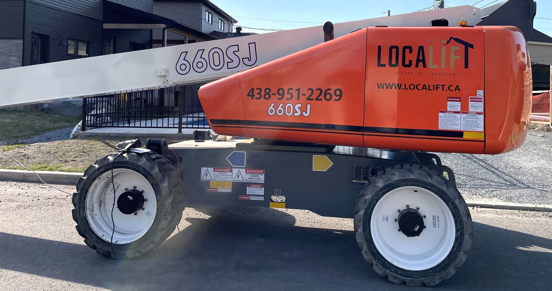 Un ascenseur orange et blanc est garé sur le bord de la route.