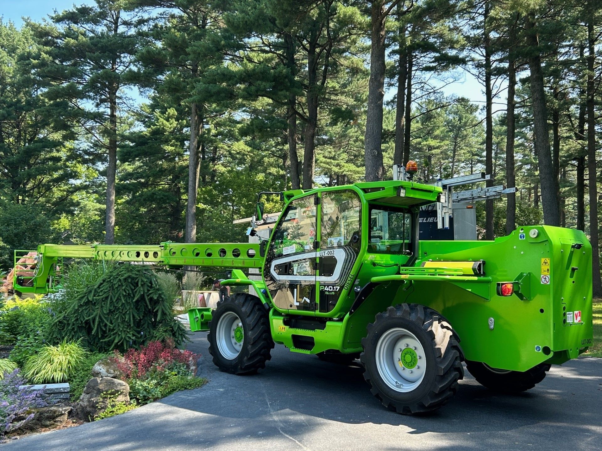 Un chariot élévateur vert est garé dans une allée devant une forêt.
