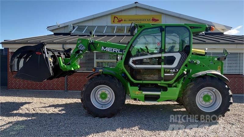 Un chariot élévateur vert est garé devant un bâtiment.