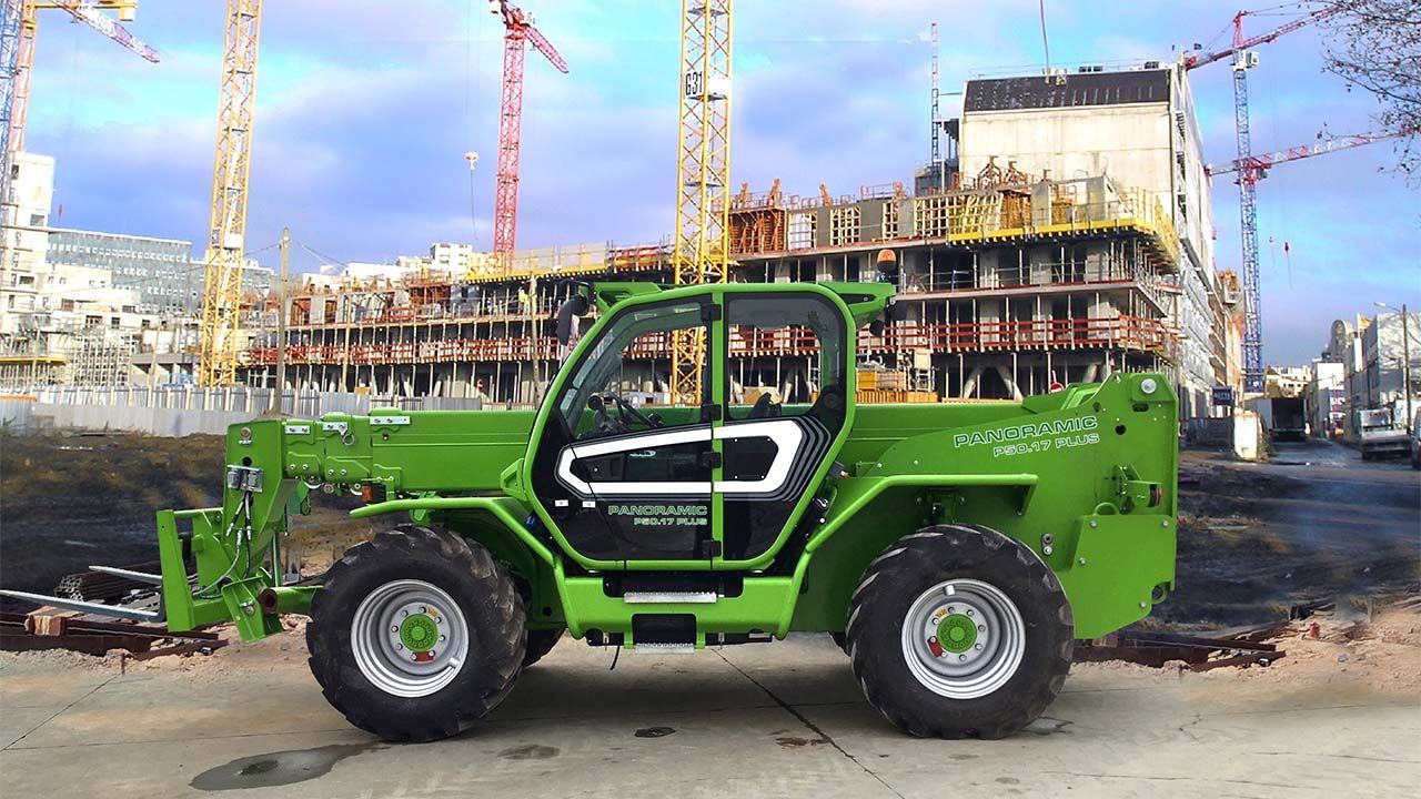 Un chariot élévateur vert est garé devant un chantier de construction.