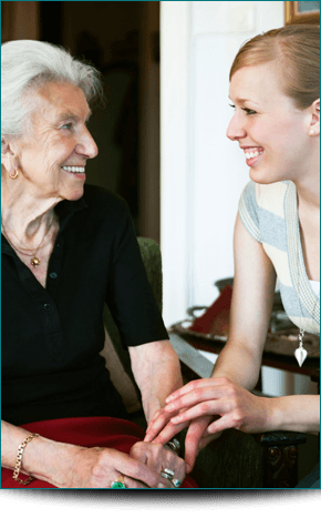 A young woman talking to an elderly lady and smiling