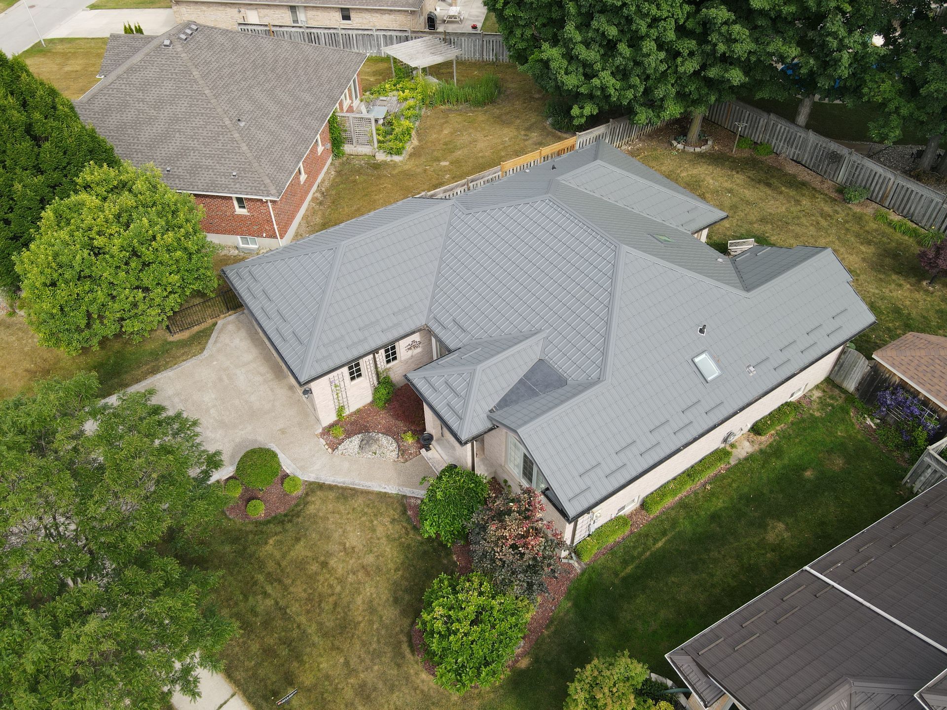 An aerial view of a house with a gray roof surrounded by trees.