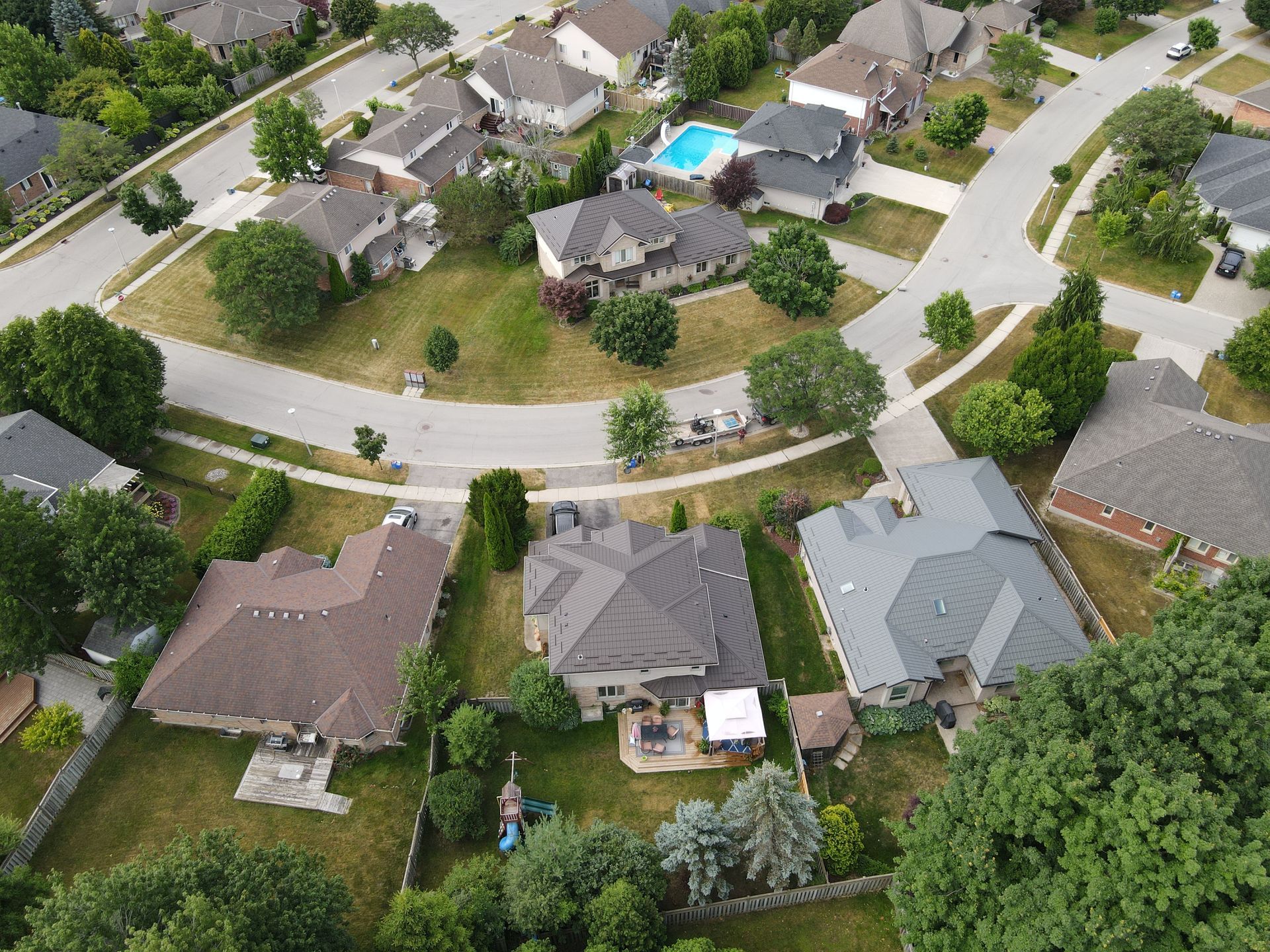 Aerial view of suburban homes with green lawns and curved roads.