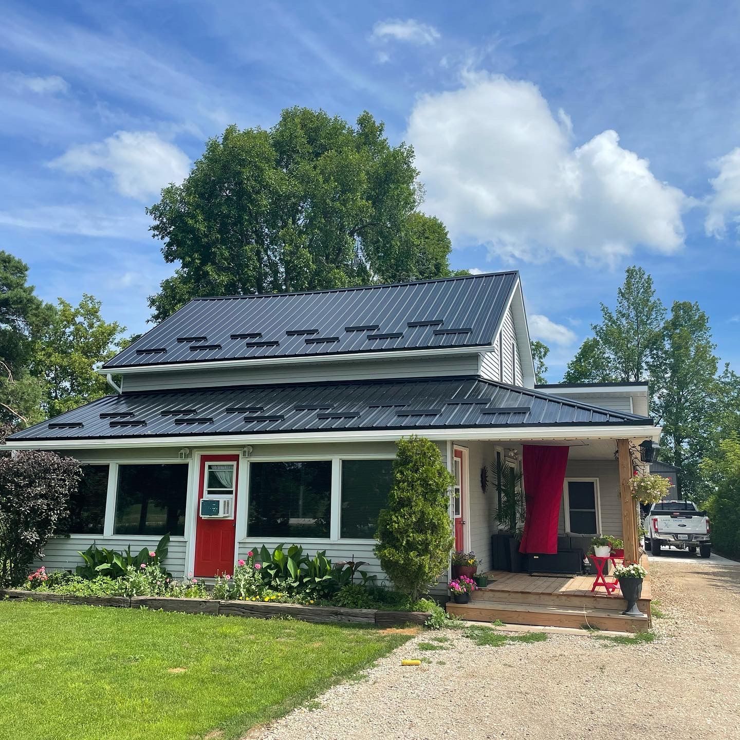 A white house with a black roof and a red door