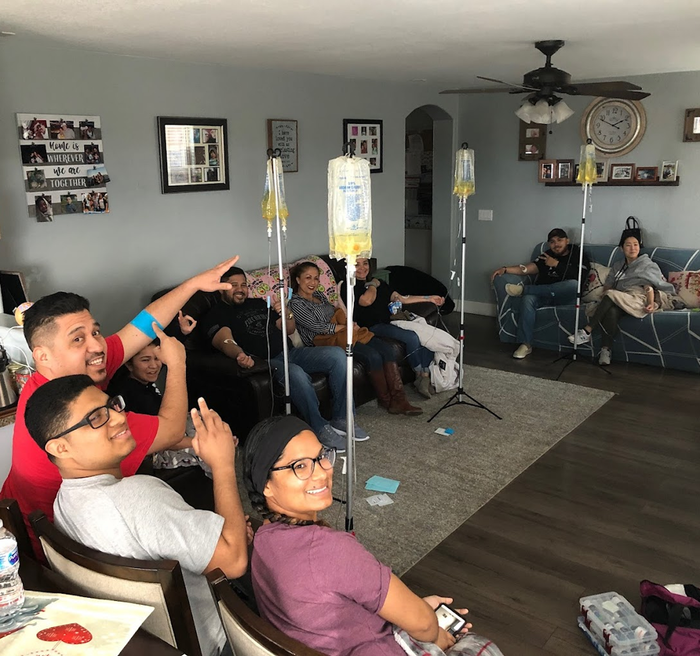 A group of people are sitting in a living room with iv bags