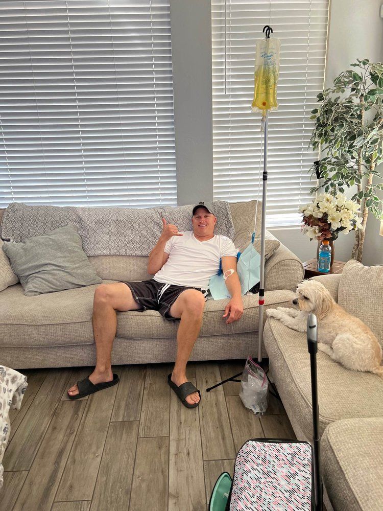 A man is sitting on a couch in a living room with a dog.