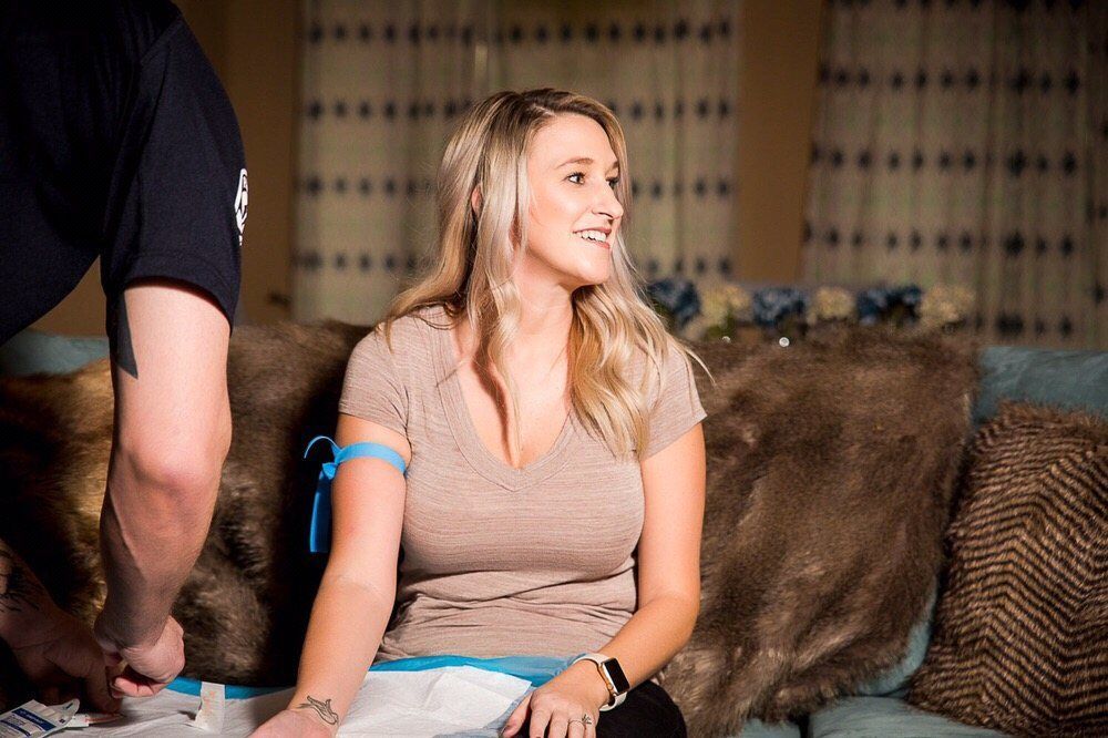 A woman is sitting on a couch with a man measuring her arm.