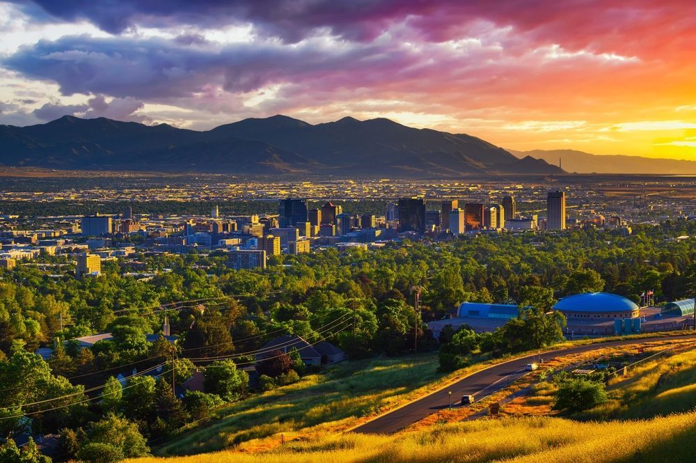 An aerial view of a city with mountains in the background at sunset.