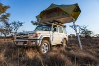 Safari 4x4 vehicle parked in african bush with tent installed on roof