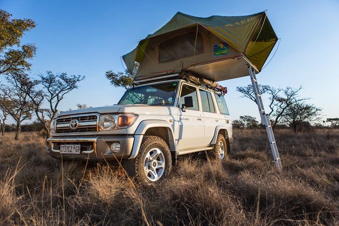 Toyota safari 4x4  vehicle in the african bush with a tent installed on it's roof