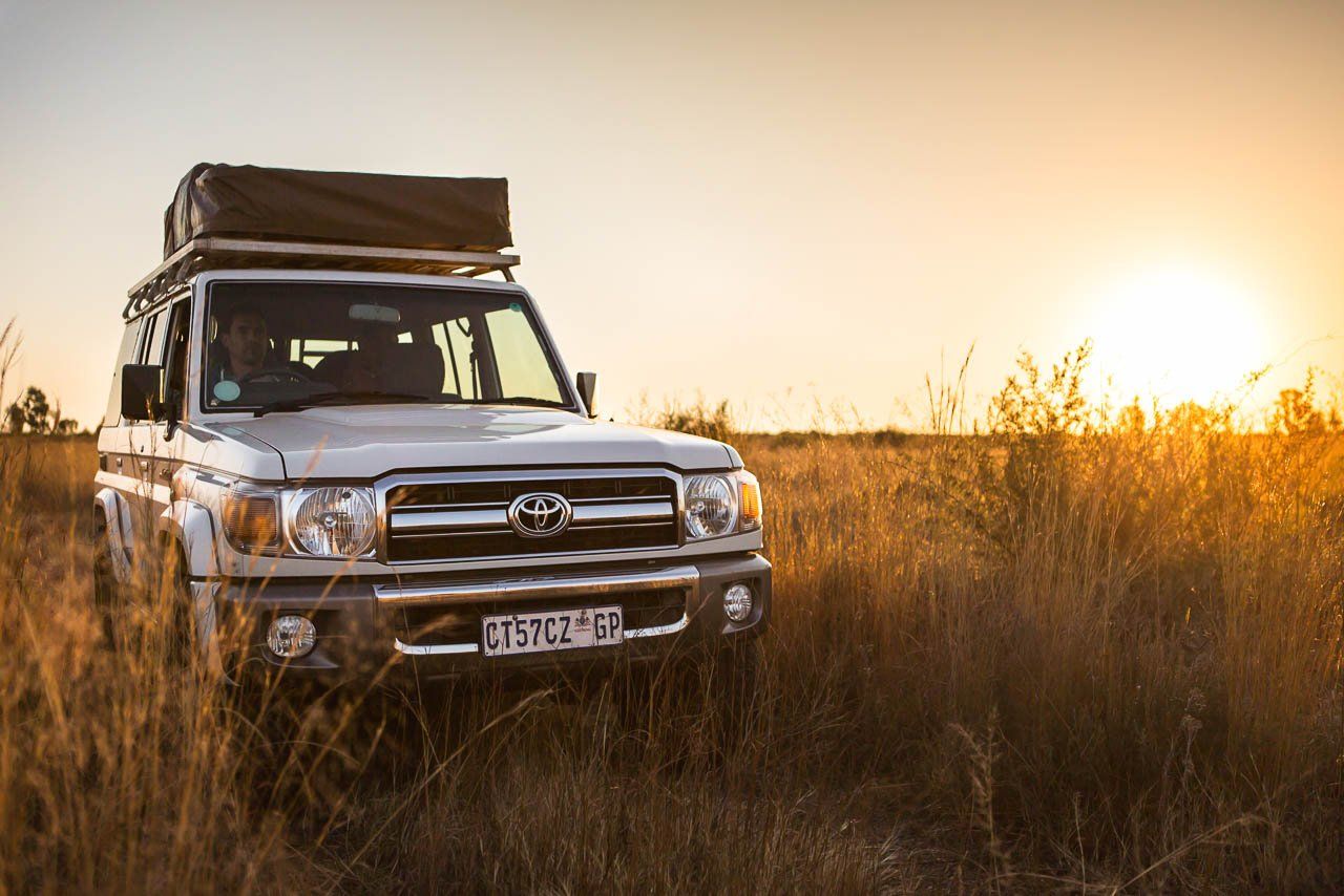 Toyota land cruiser 4x4 vehicle with roof rack driving through african bush