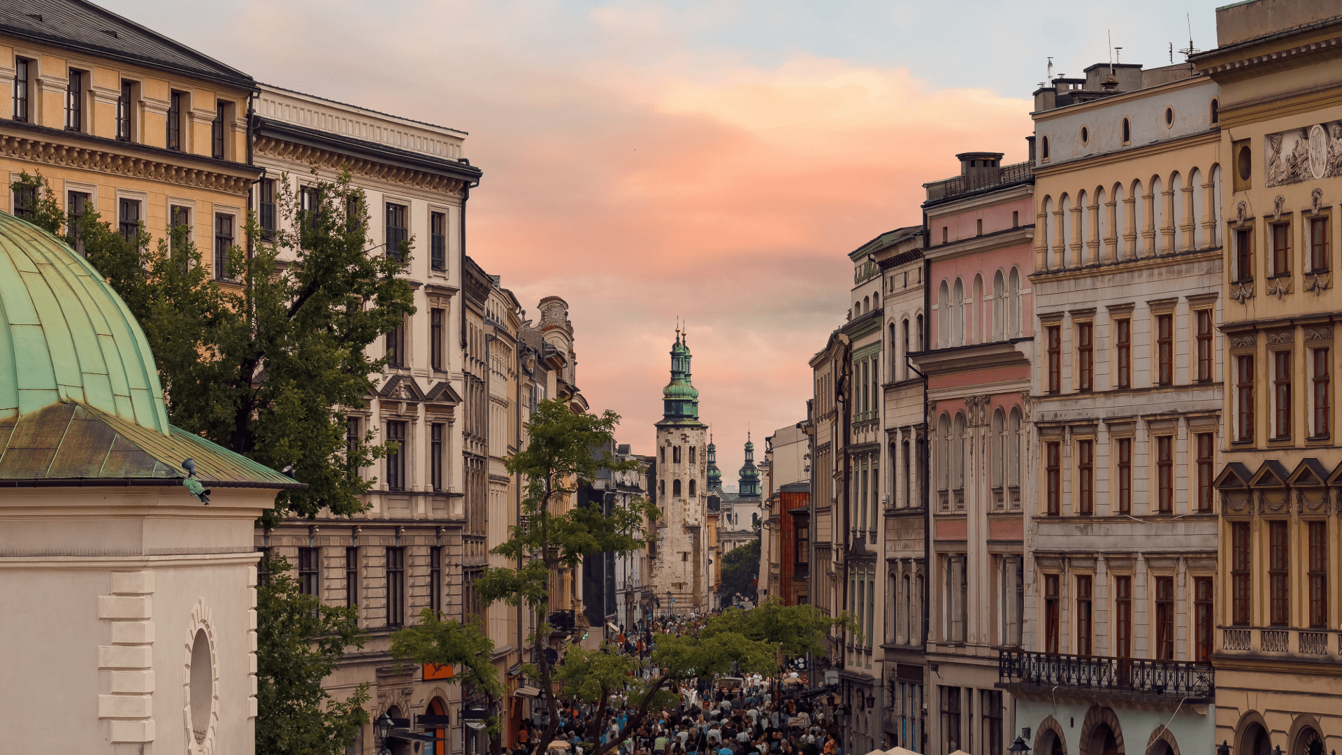 Historic Main Square in Kraków with colorful buildings and a church tower at sunset