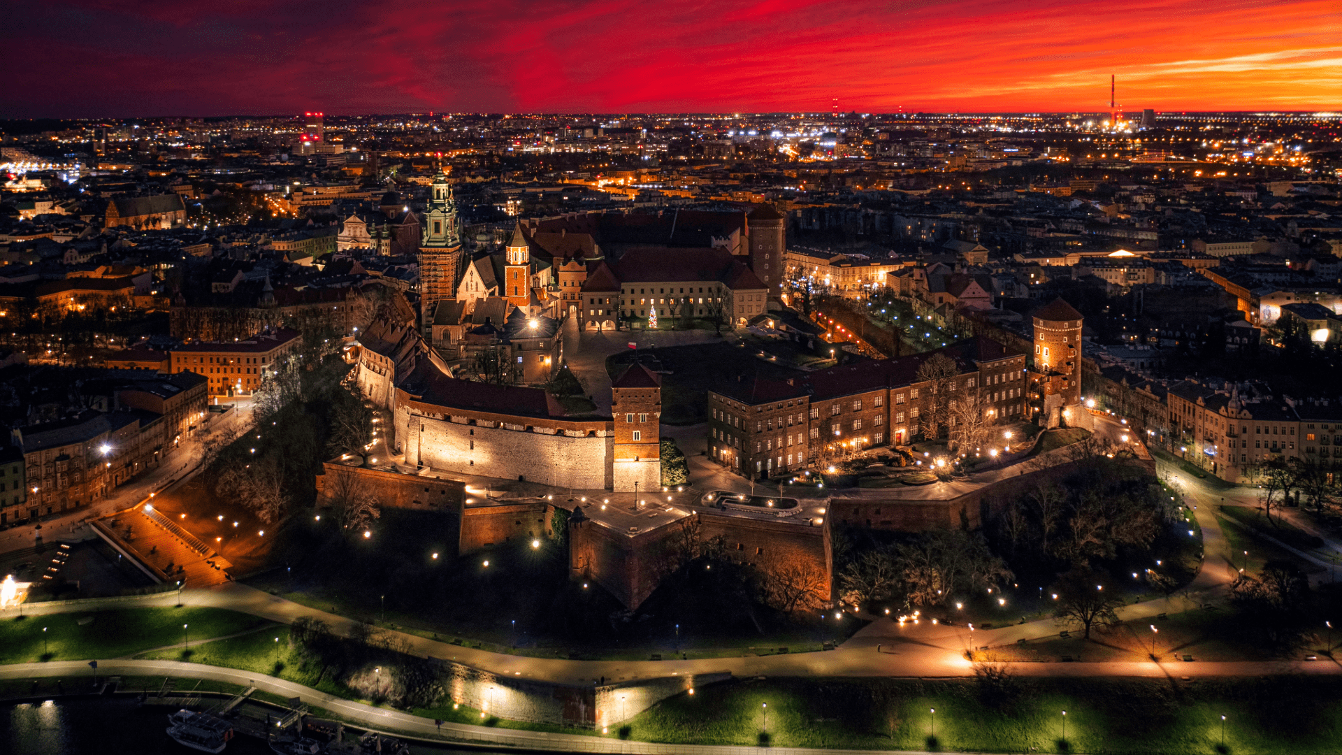 Aerial twilight view of Kraków’s Old Town illuminated with city lights and a vibrant orange sky