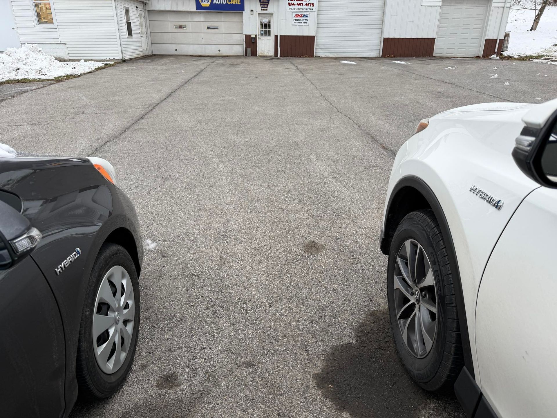 Two hybrid vehicles parked side by side in front of Forward Motors' shop