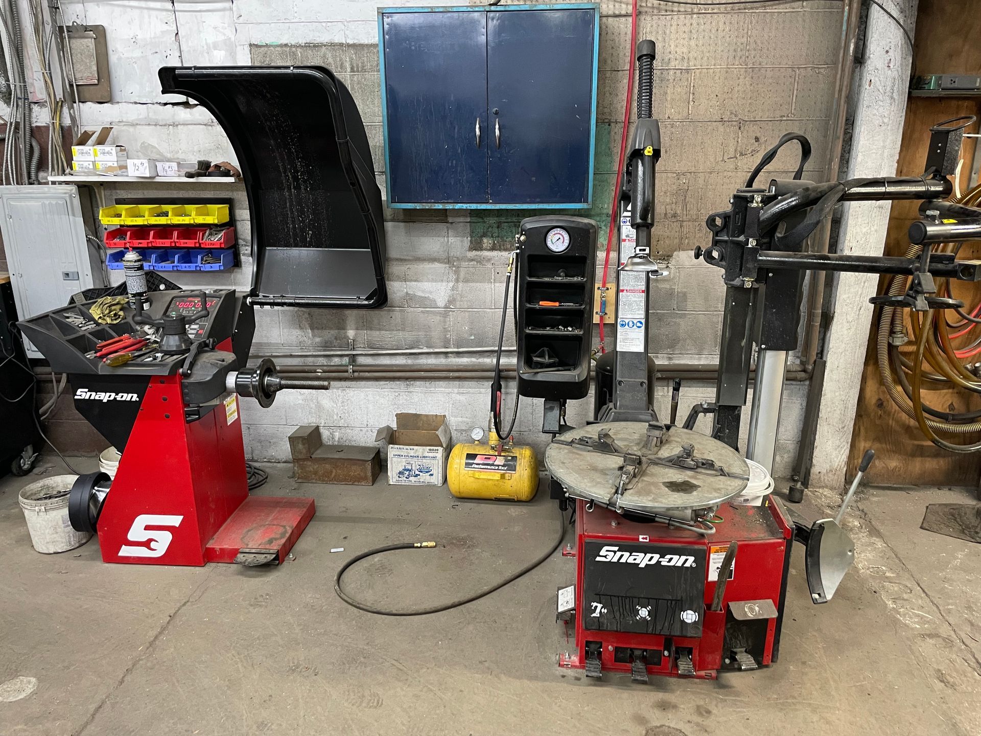 Red Snap-on tire equipment: balancer and changer against a brick wall  | Forward Motors