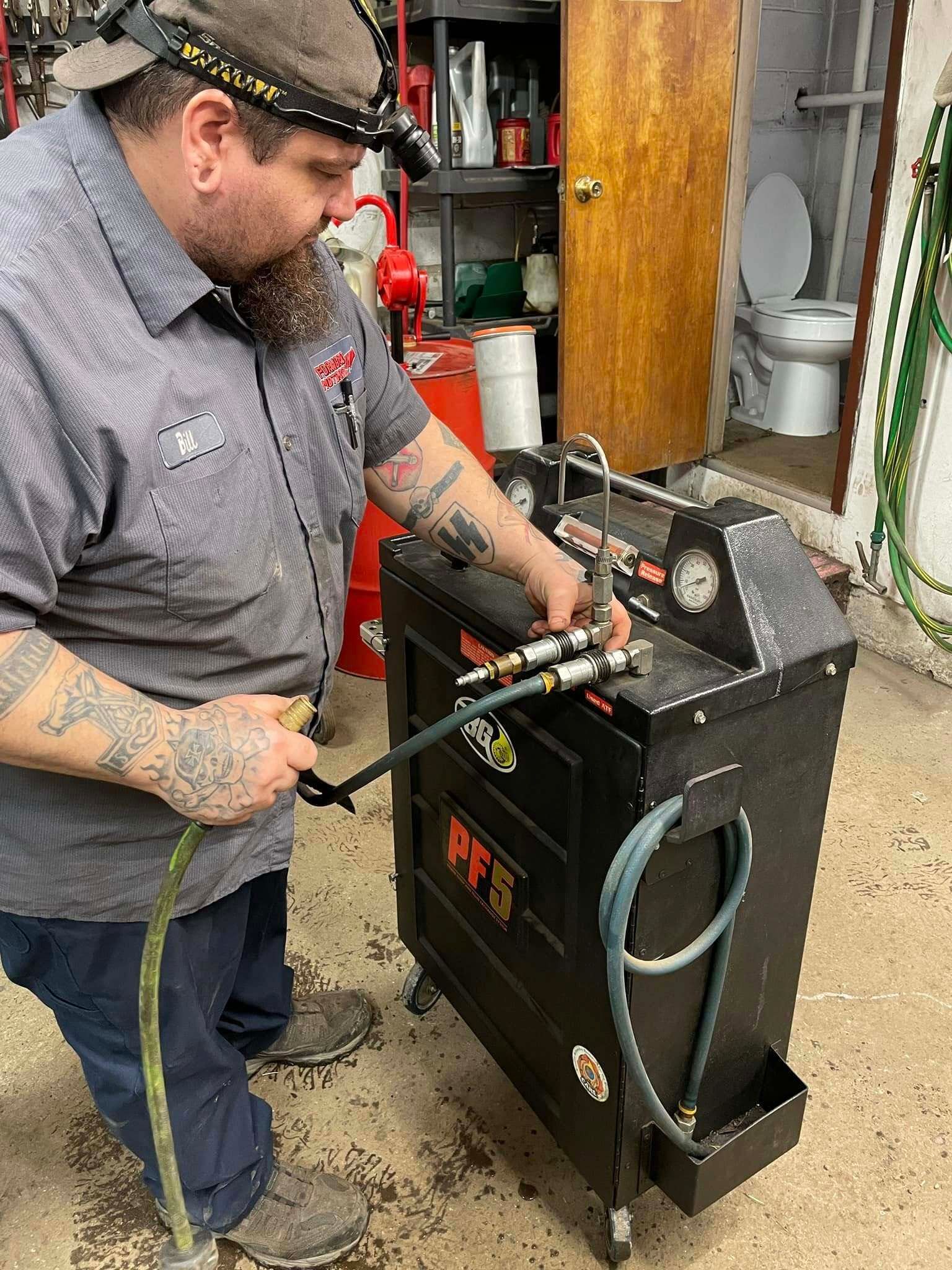 Mechanic working on a black machine with hoses | Forward Motors