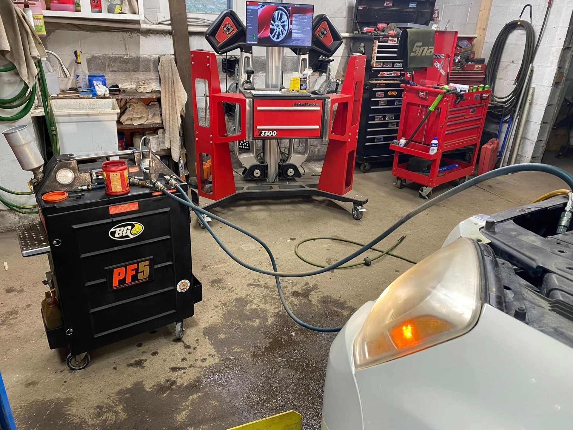 Car in a garage undergoing maintenance, with equipment and tools visible.