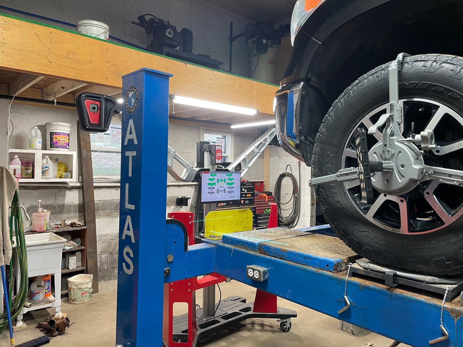 A truck on a lift undergoing wheel alignment at an auto repair shop.