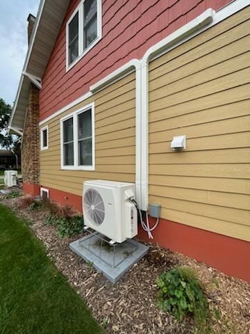 A red and yellow house with a white air conditioner on the side of it.