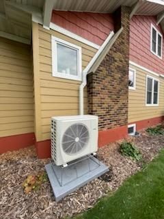 A large air conditioner is sitting on the side of a house.