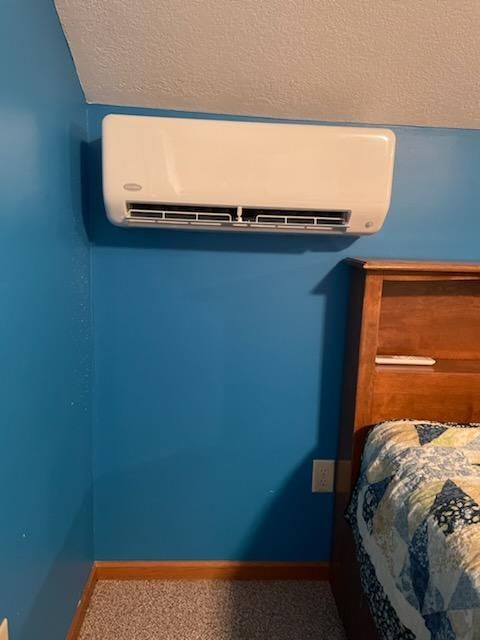 A bedroom with a bed and a wall mounted air conditioner