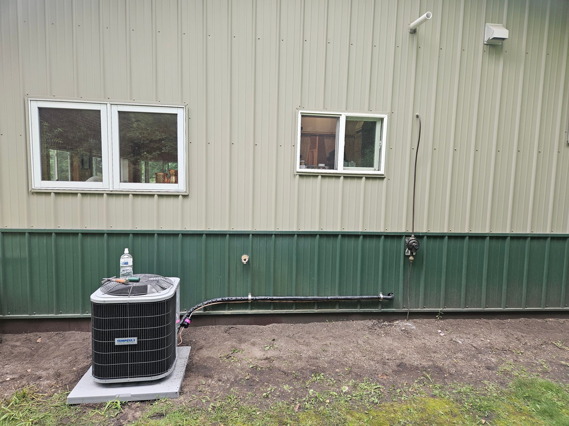 An air conditioner is sitting outside of a building next to a window.