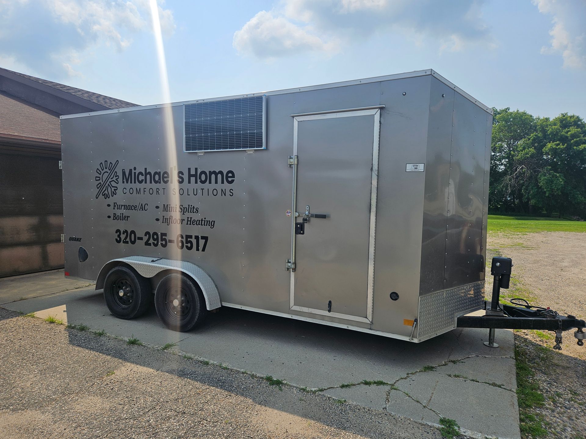 A silver trailer is parked on the side of the road.