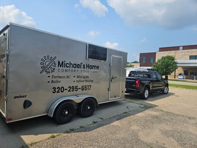 A trailer for michael 's home company is parked next to a truck.