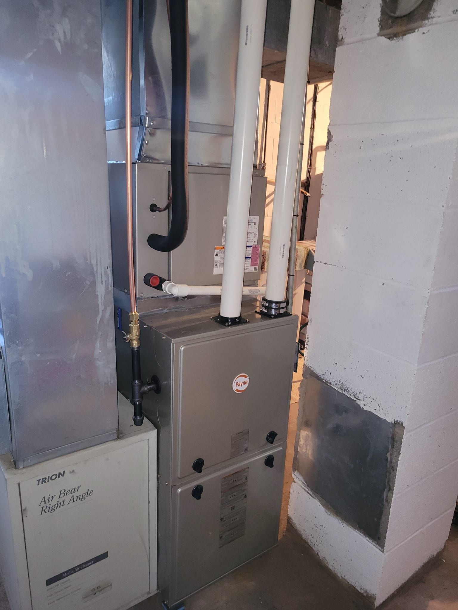 A furnace is sitting in a room next to a brick wall.