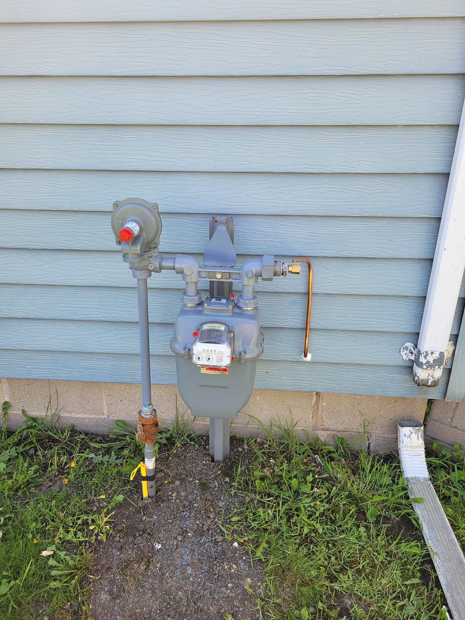 A gas meter is attached to the side of a house.