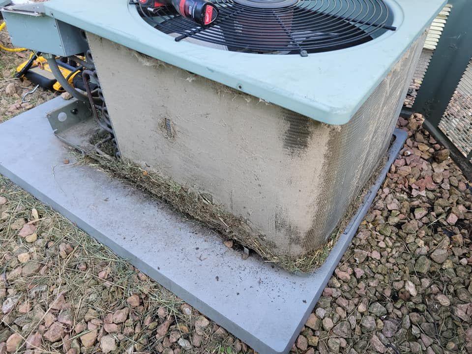 A dirty air conditioner is sitting on top of a concrete platform.